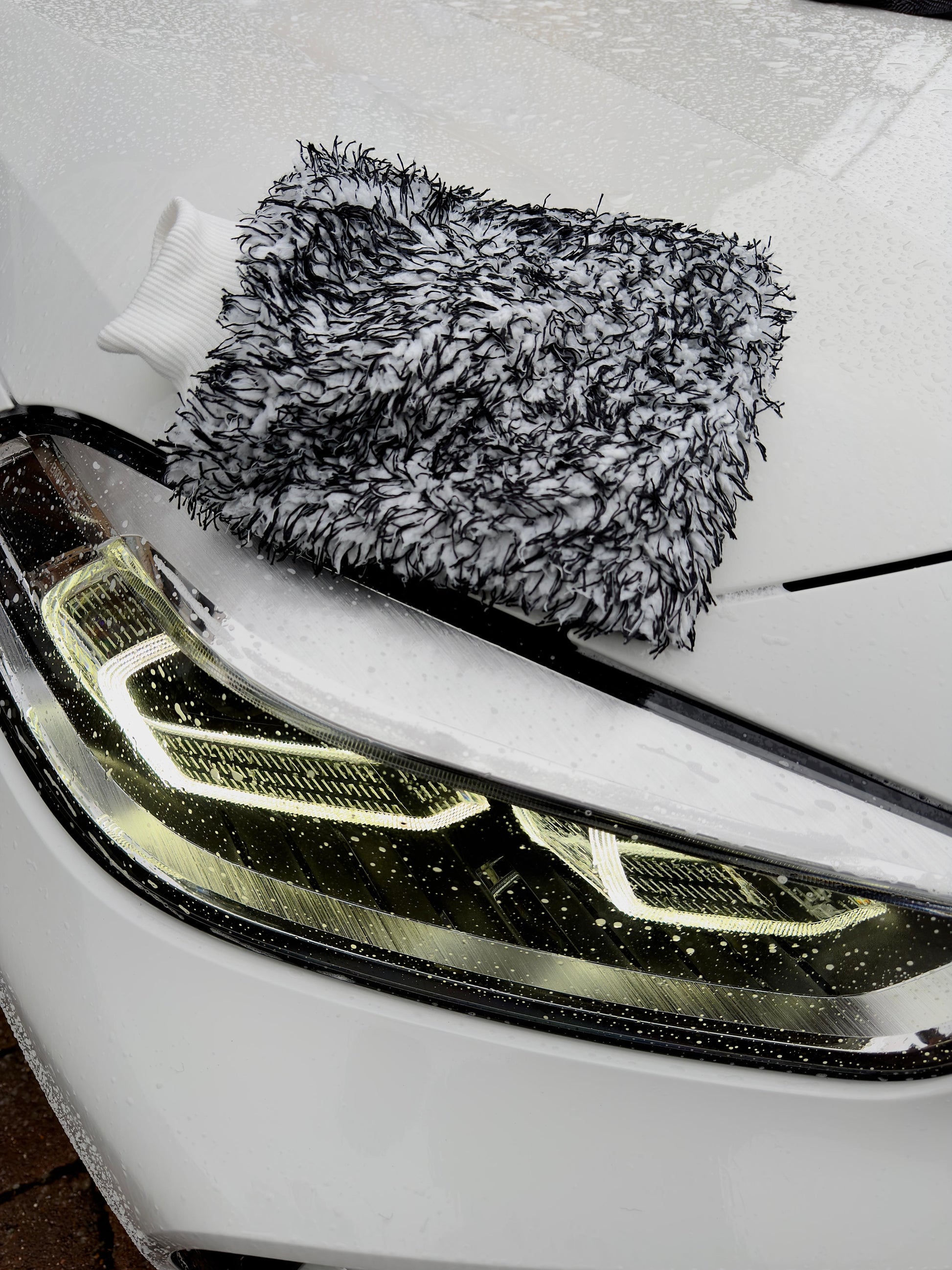 Microfibre wash mitt on car front headlight by Driven Digits