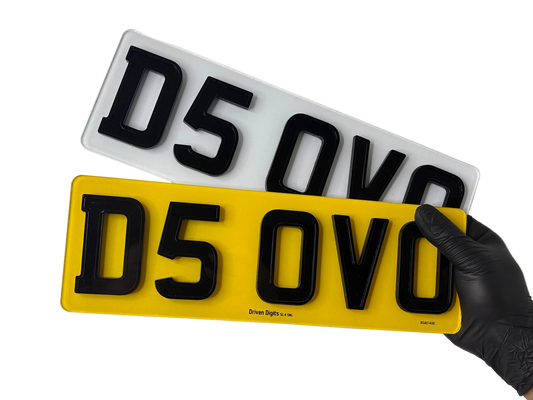 Two shortened ghost number plates, one yellow and one white with black text, held by a gloved hand on a white background.
