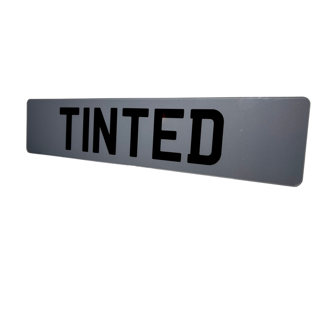 Rectangular gray sign with 'TINTED' in black text on a white background
